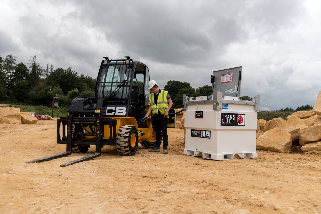 OilMaxx employee beside a ful storage tank and a forklift in a construction site