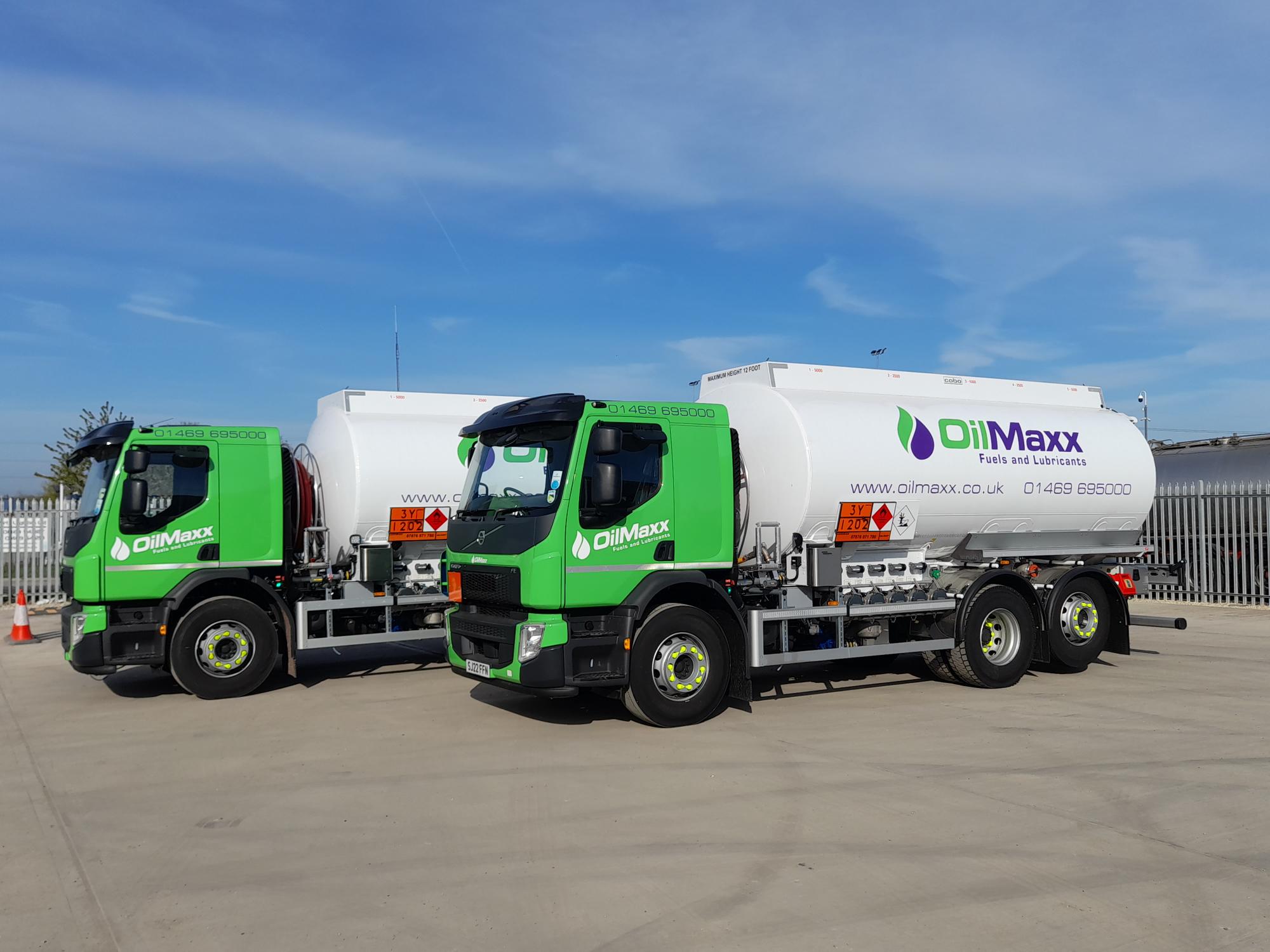 two oilmaxx oil tankers with the logo on the side of the tanker in a yard